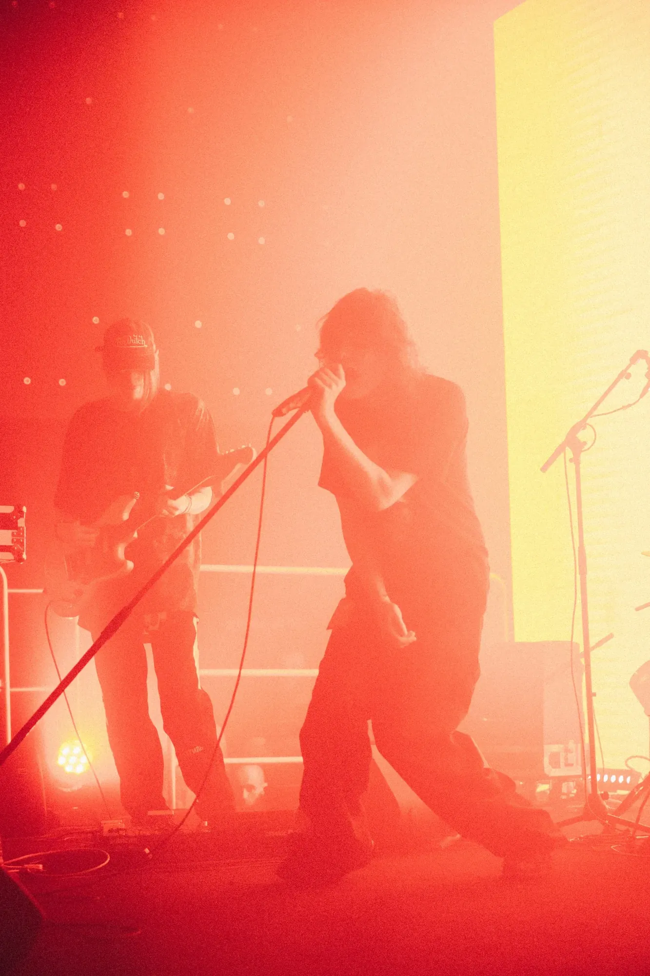 Singer and guitarist performing through bright red-orange light, photographed by Helen Milova