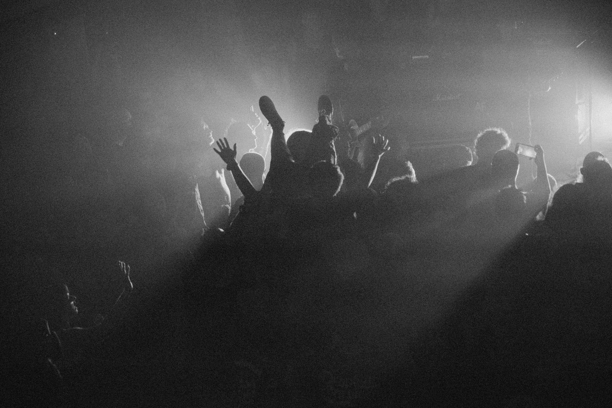 Crowdsurfer held upside down above a black-and-white audience, photographed by Helen Milova